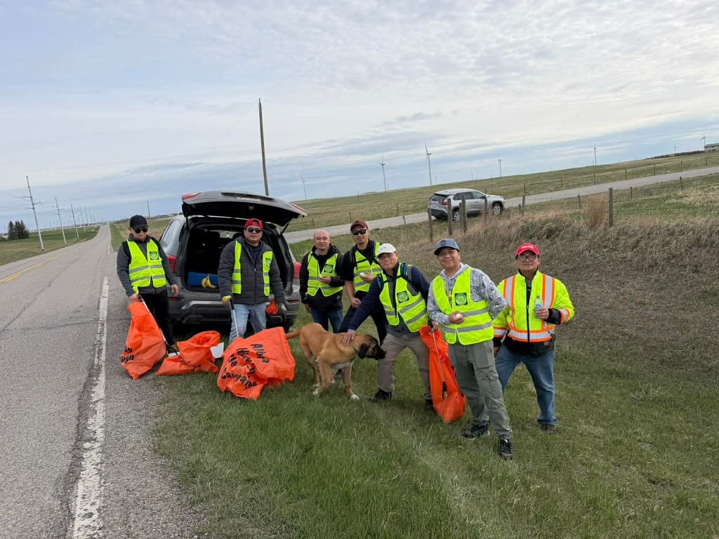 Volunteers in safety vests standing beside a highway with collected trash bags after the 2026 highway cleanup.