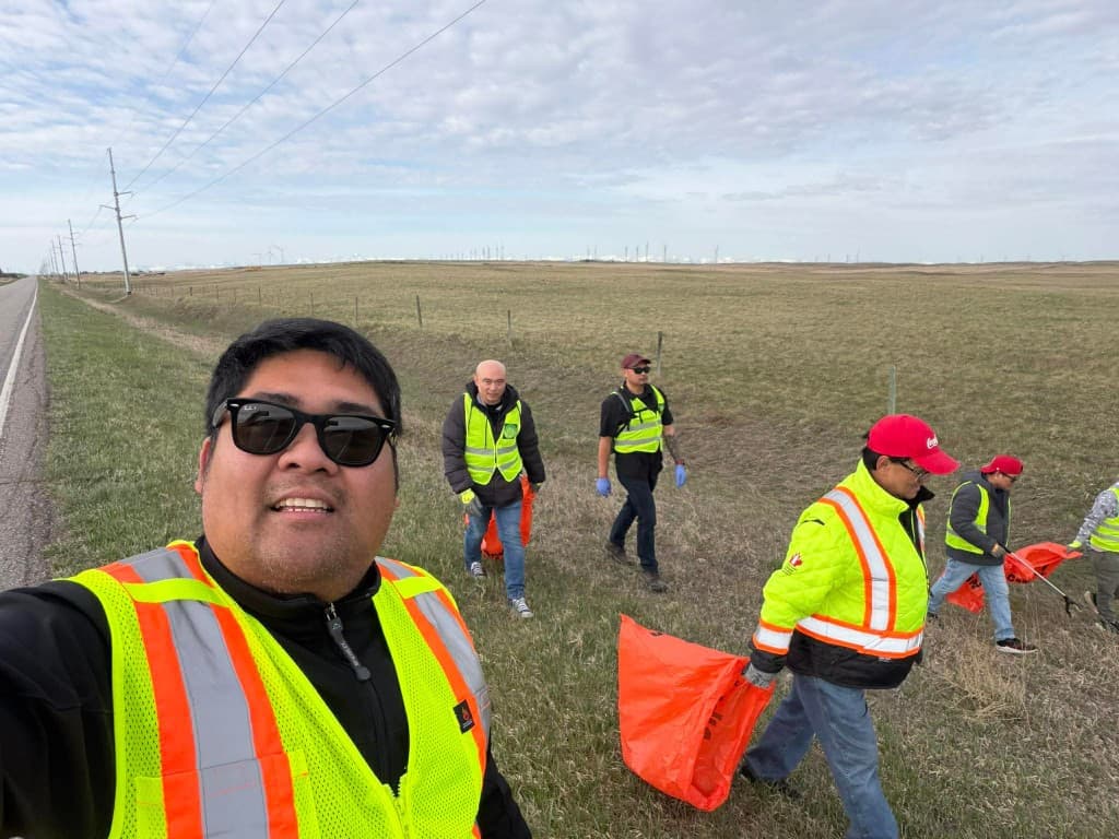 Volunteers in safety vests collecting litter along a roadside during the 2026 highway cleanup.